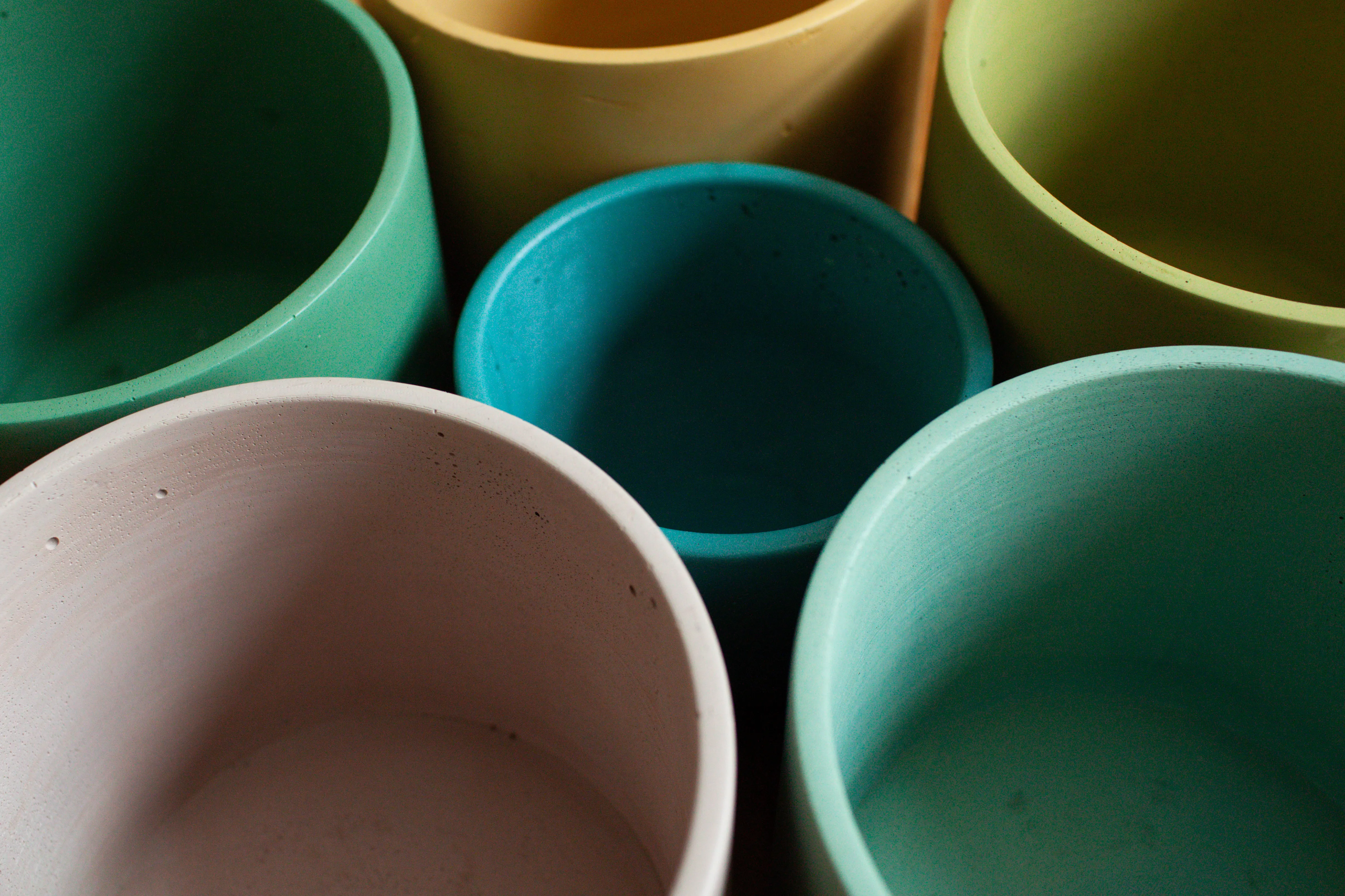 Collection of colorful handmade ceramic pots in forest green, mustard, teal, and blush